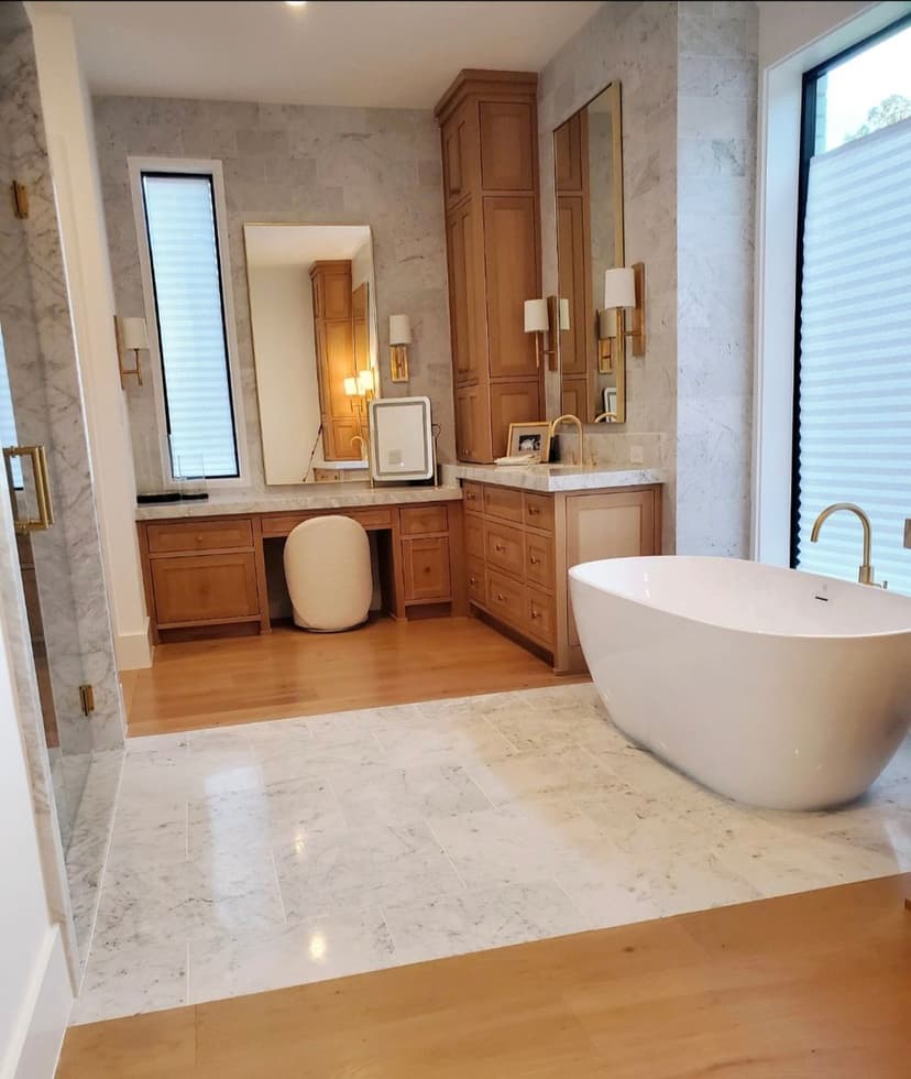 Modern bathroom with marble walls, wooden cabinetry, freestanding bathtub, and large mirrors.