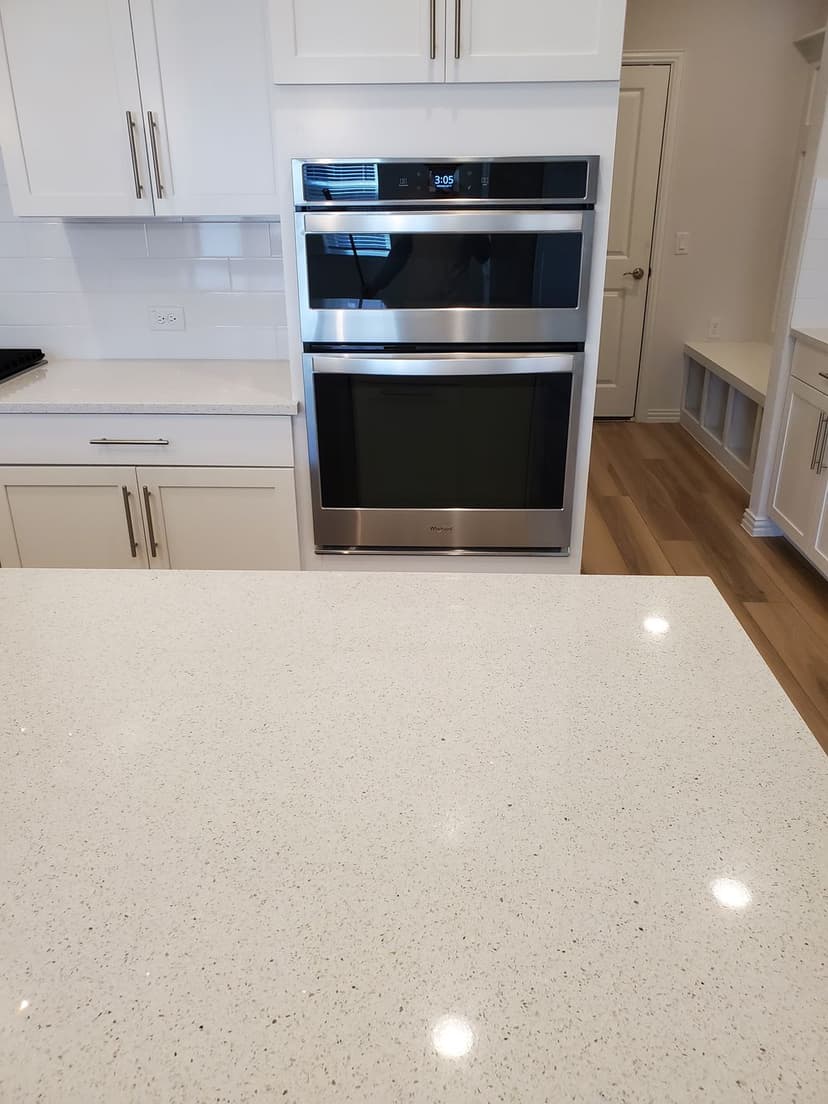 Modern kitchen featuring stainless steel double ovens above a sleek quartz countertop.